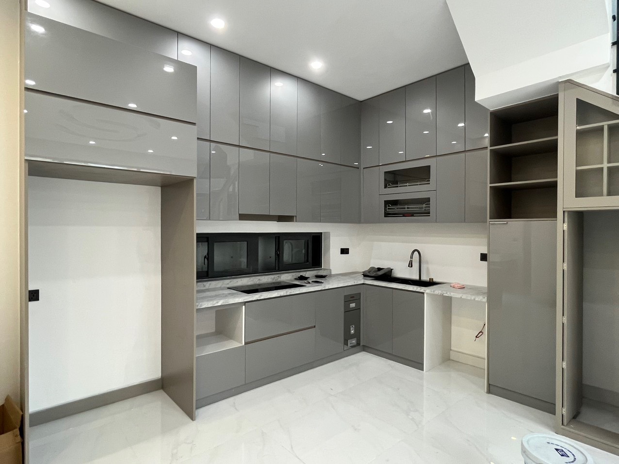 Tủ bếp với thiết kế chữ L giúp tận dụng tối đa diện tích kết hợp phủ Acrylic bóng gương mang lại vẻ đẹp sang trọng và tinh tế